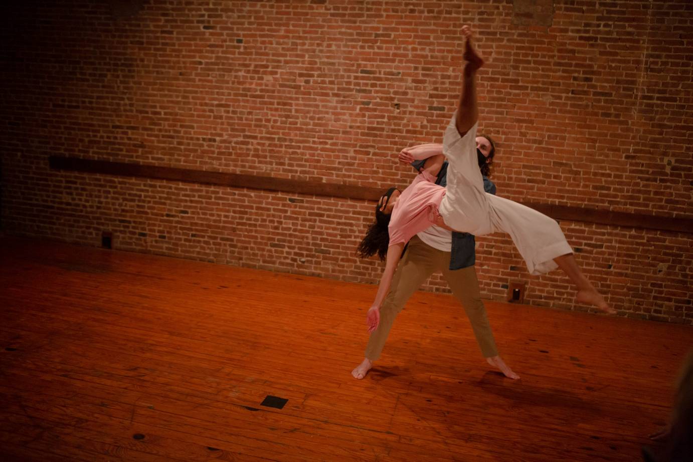 A man lifts a woman as one of her legs stretches to the ceiling and the other bends to the floor