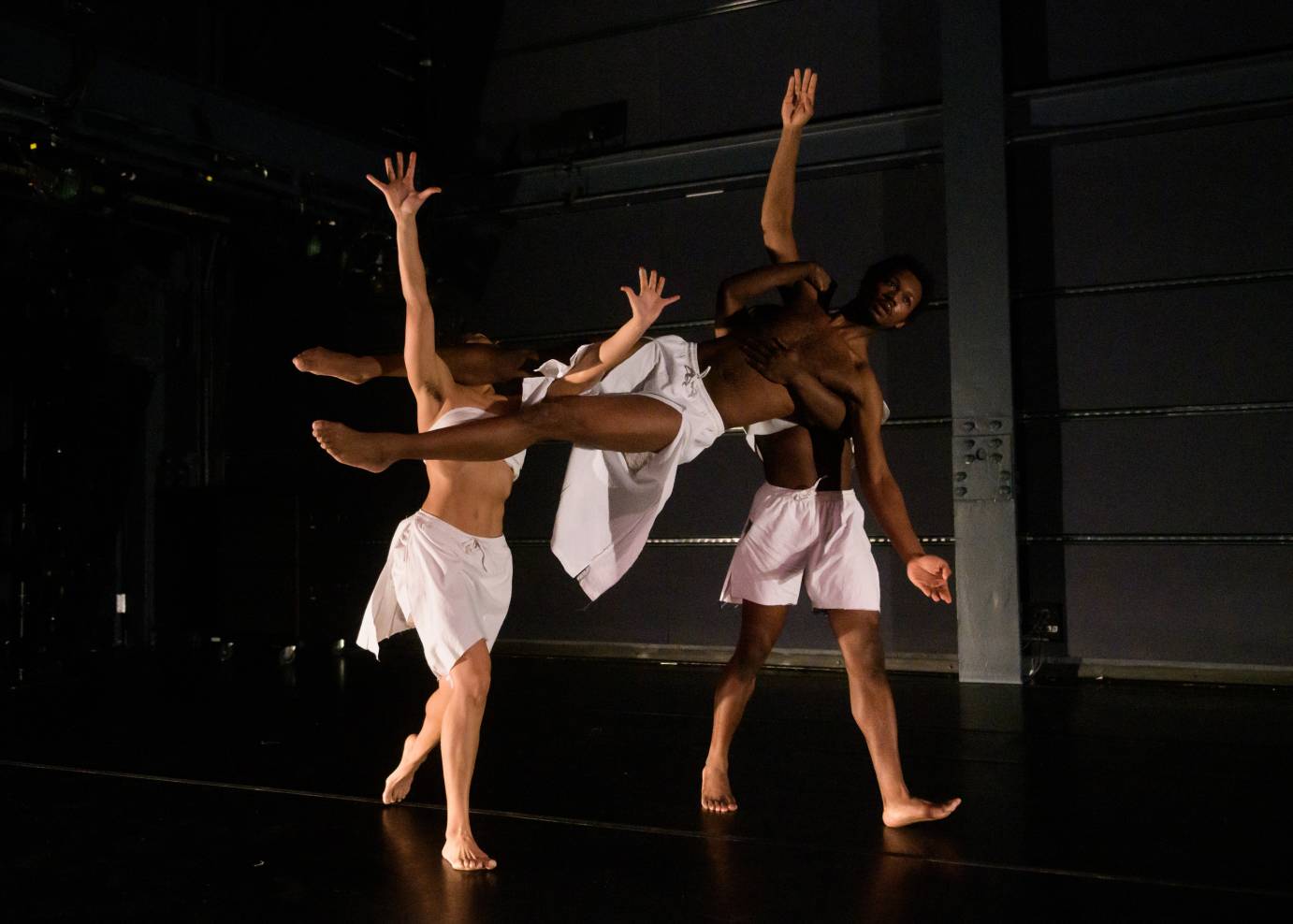 Two dancers carry another over their shoulders