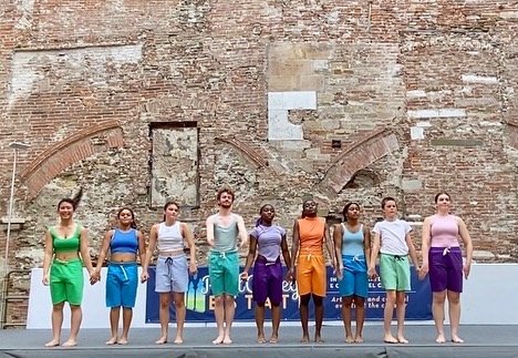 nine teans in bright colored shirts and shorts hold hands to take their final bow