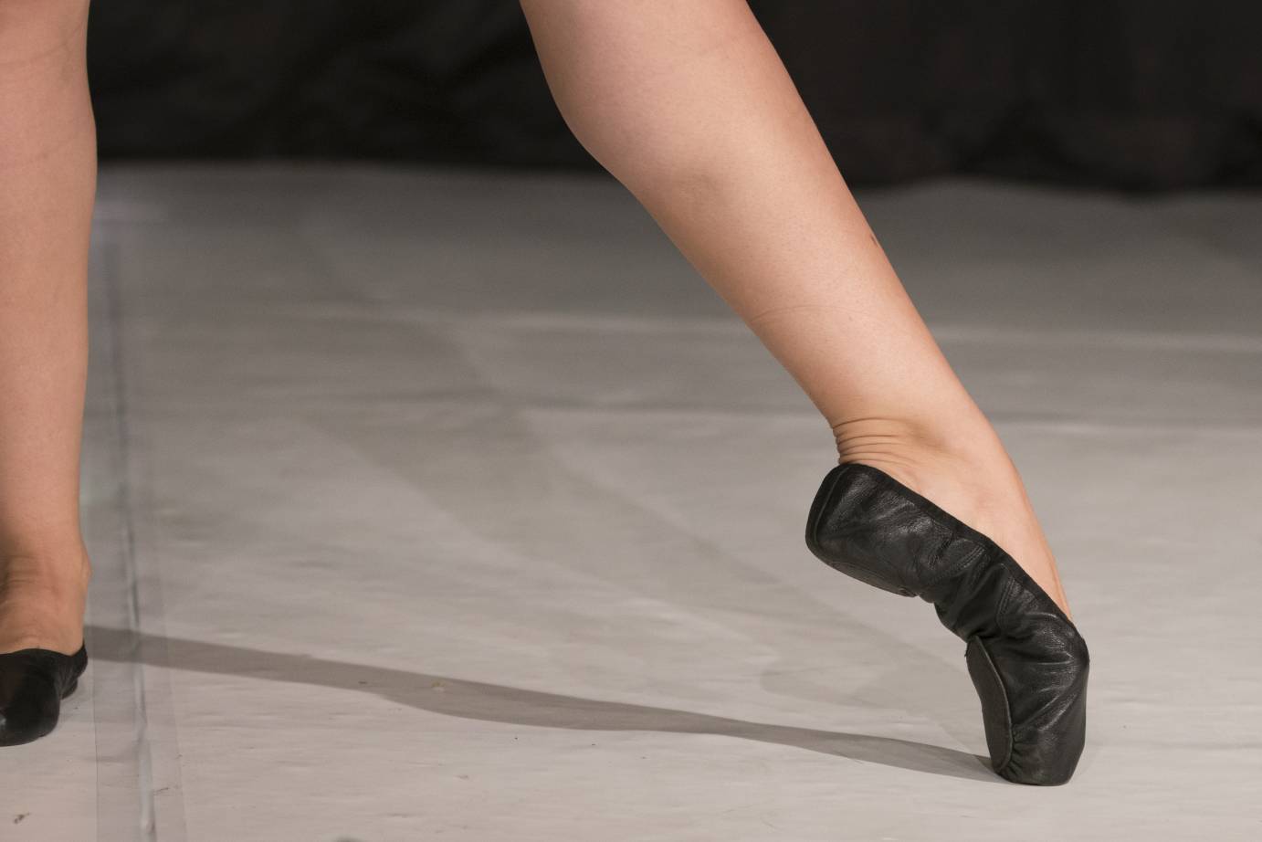 Woman's leg in black ballet slipper in tendu position
