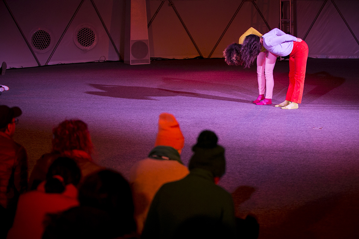 Two women bow with hands on their lower backs