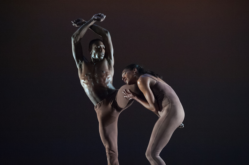 Mark Willis lifts his leg in a bent position. His arms cross at his wrists above his head. Kristen Foote holds onto his leg in the air. 