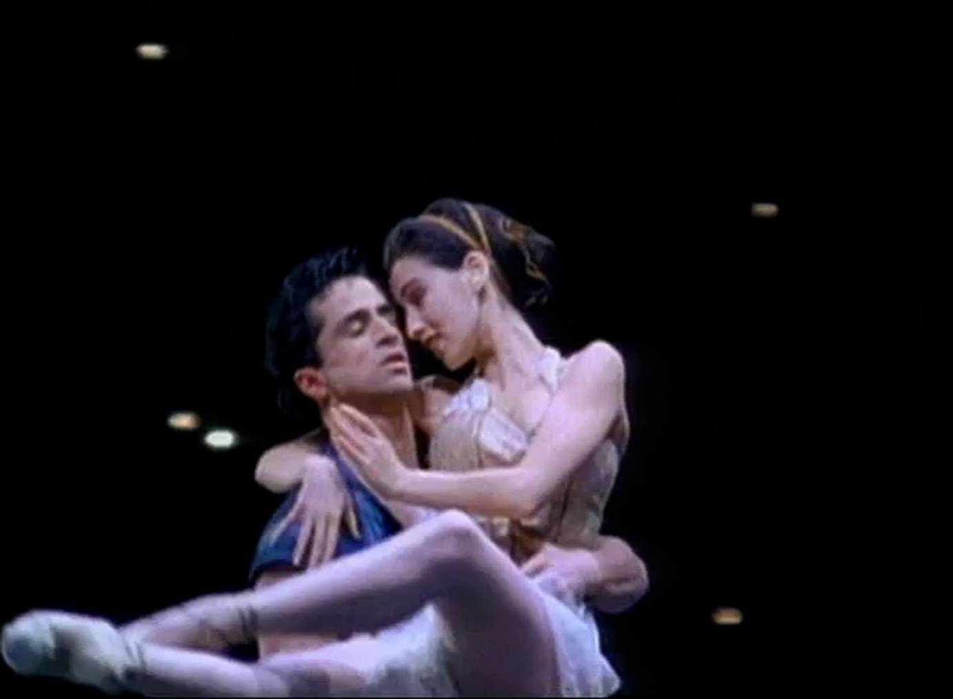 A man on skates cradles a ballerina in pointe shoes