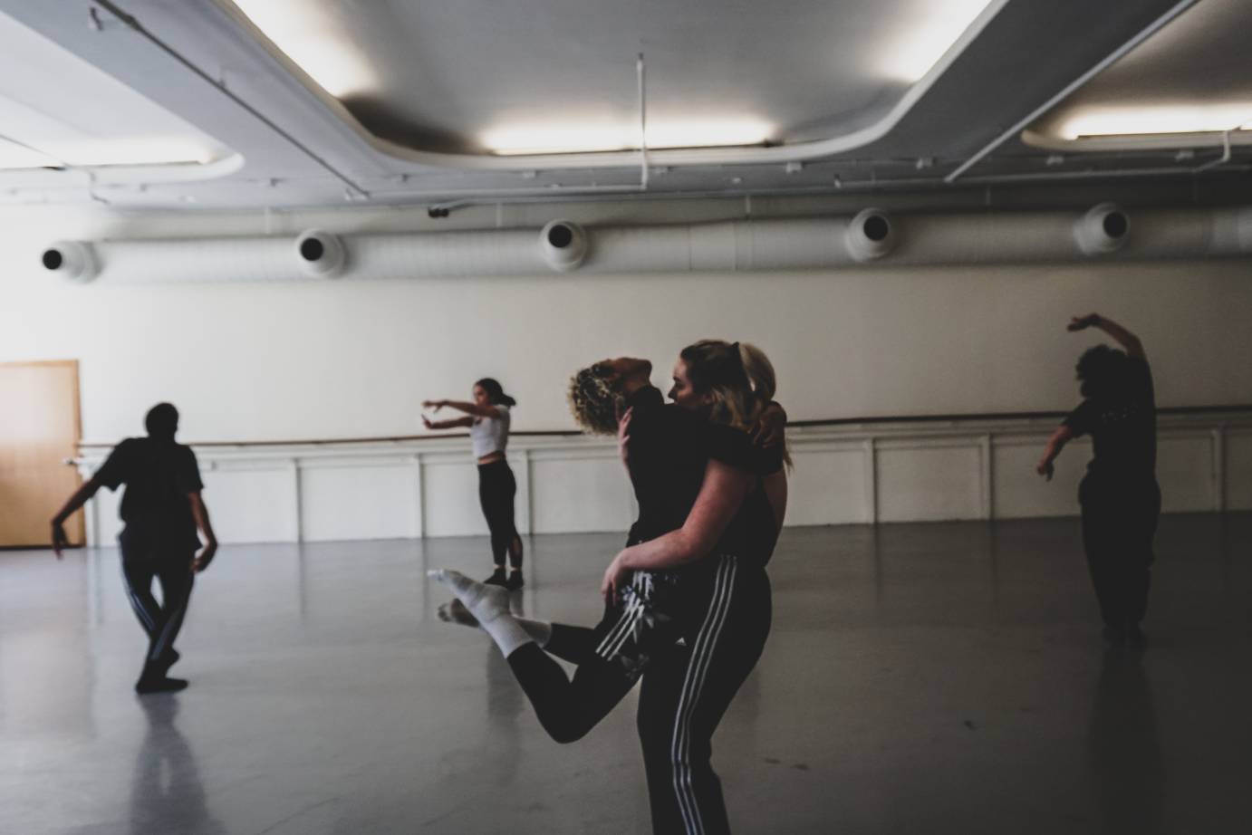 Two dancers hug while three move independently