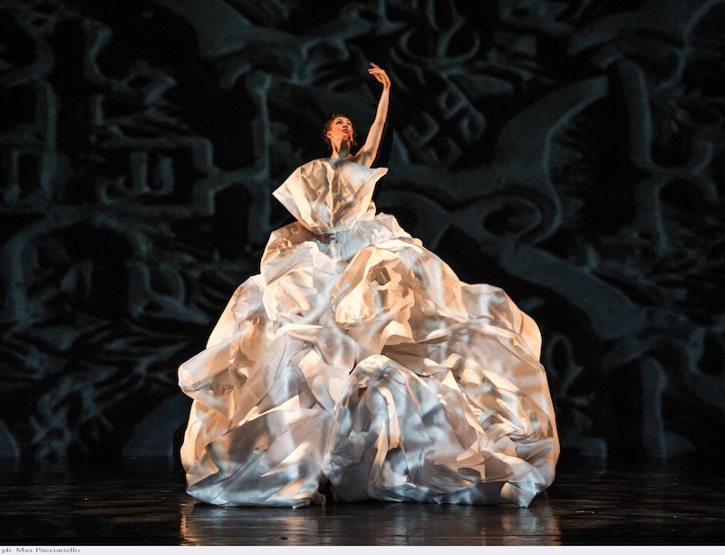 A woman in a cascading white paper gown that resembles a flowering orchid.