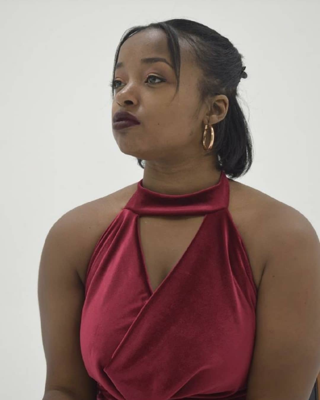 Clad in a red velvet dress, Maiya Redding looks into the middle distance