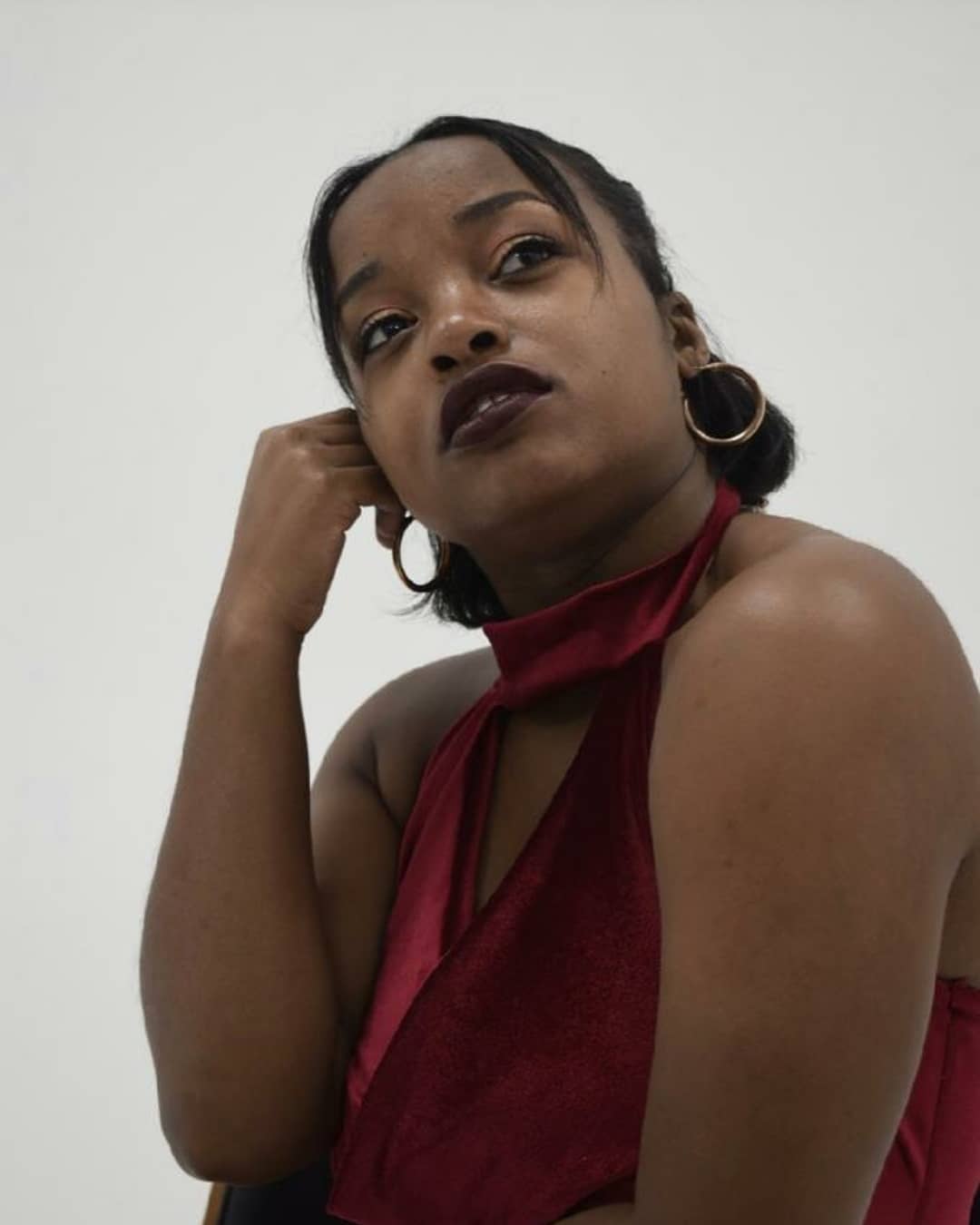 Clad in a red velvet dress, Maiya Redding presses a fist to her cheek