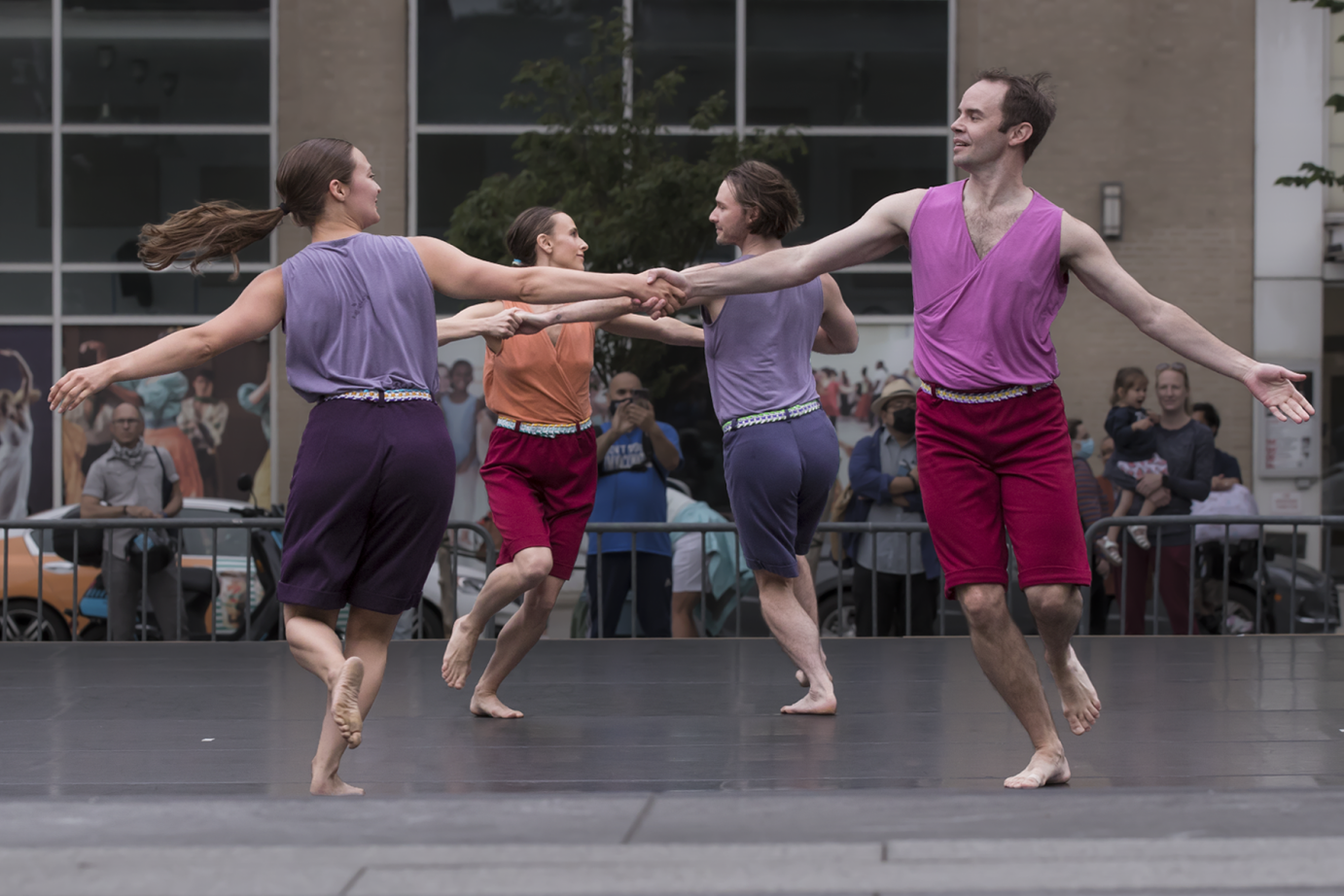 three couples ( men and women) hold hands and circle around one another in a modern square dance.
