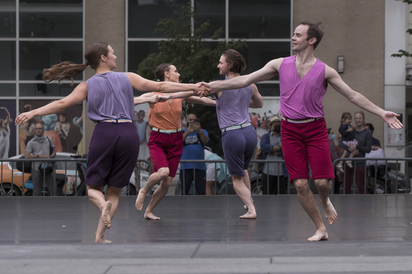 three couples  ( men and women) hold hands and circle around one another in a modern square dance.