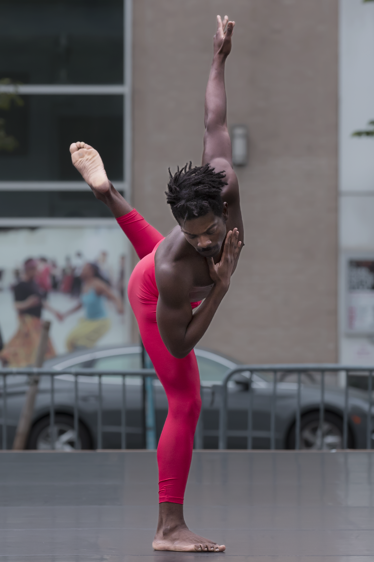 the black skinned man in red tighgts now seems to acknoledge the earth. standing on one bent leg, huddled over it looking at the ground, while one arm reaches to the heavens and the other is bent with his palm caressing his face 