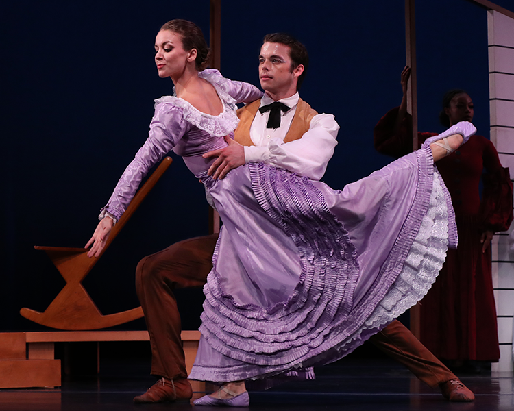 the bride in ruffled purple, her leg bent and lifted behind her is held round her waist by the husbandman dressed in a white top and old fashioned bowtie a tan vest and dark rust pants...he gazes outward as if seeing their future together