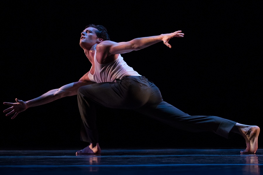 the man lunges toward the ground leaning right and looking upwards arms outstreched.