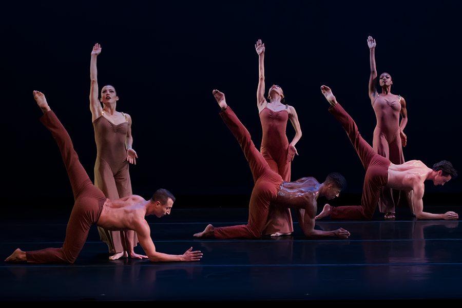 a chorus of three men and three women in shades of red-brown. the women stand with one arm lifted into the air and the other arm bent its hand cupped on one hip... The men balance on one knee and their forearm as their left leg extend into the air.