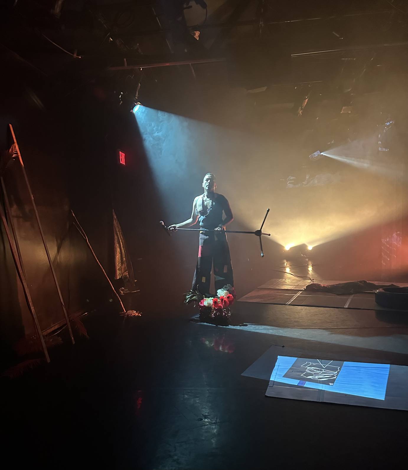 A figure bathed in blue light obscured by other light reflecting off a wall and floor