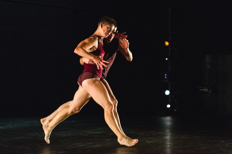 Two figures run side by side. They both wear maroon-colored briefs and tank tops.