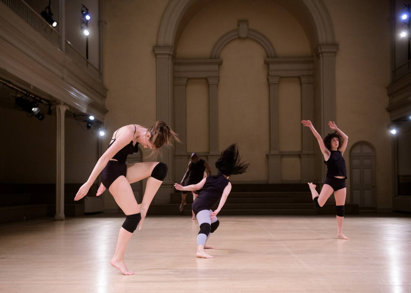 Three dancers kneel while two others writhe