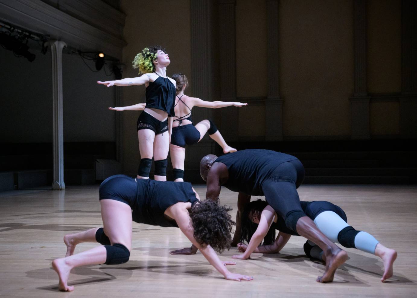 Three dancers lunge while two extend their arms to the side