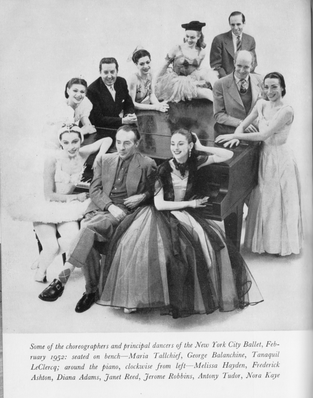 The dancers and choreographers of New York City Ballet in 1952 sitting or standing around a grand piano.