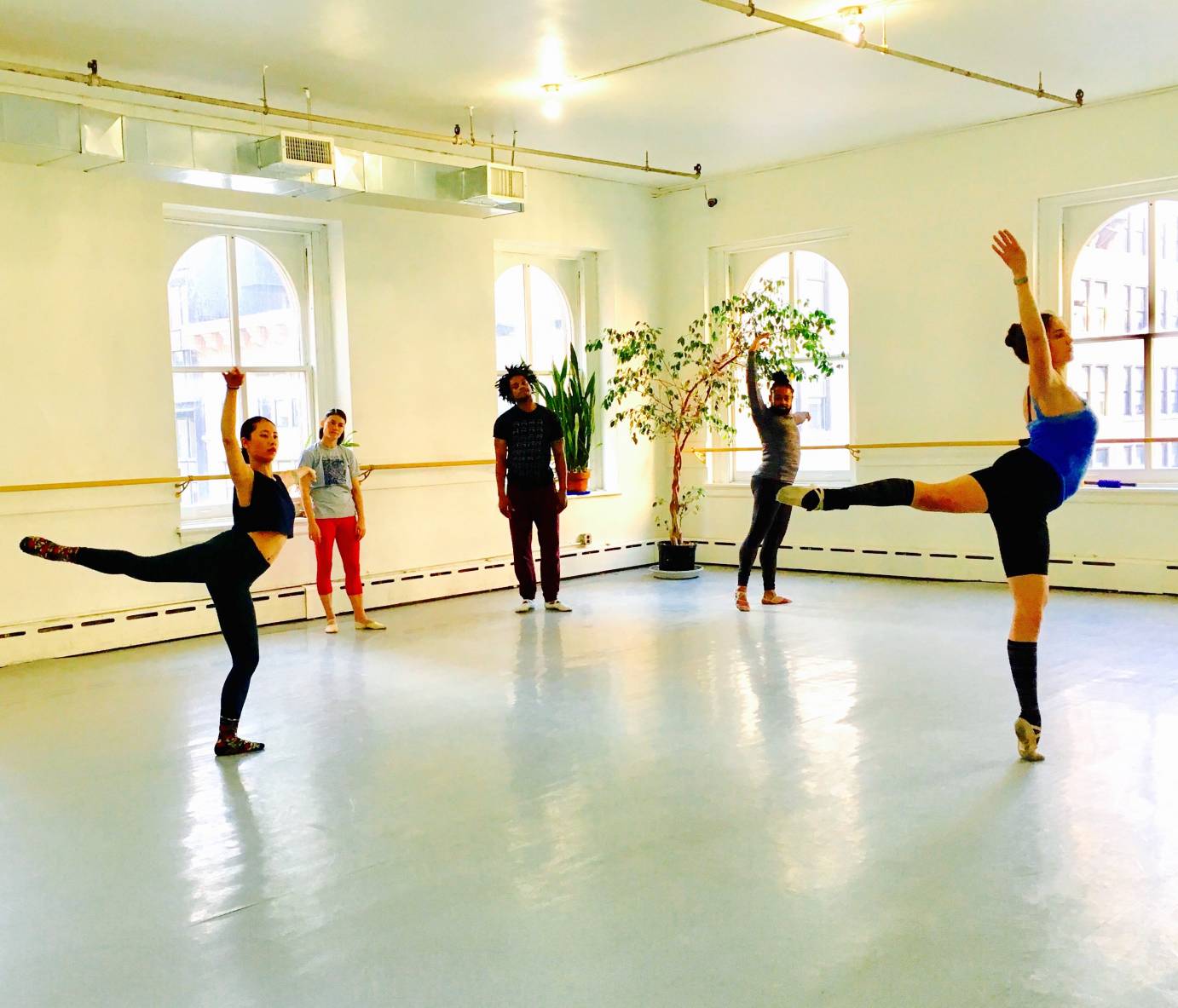 Two dancers complete an arabesque as a trio of dancers watches