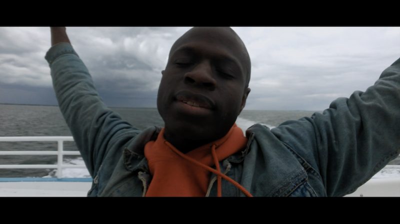 A young man with his arms outstretched abroad a boat.