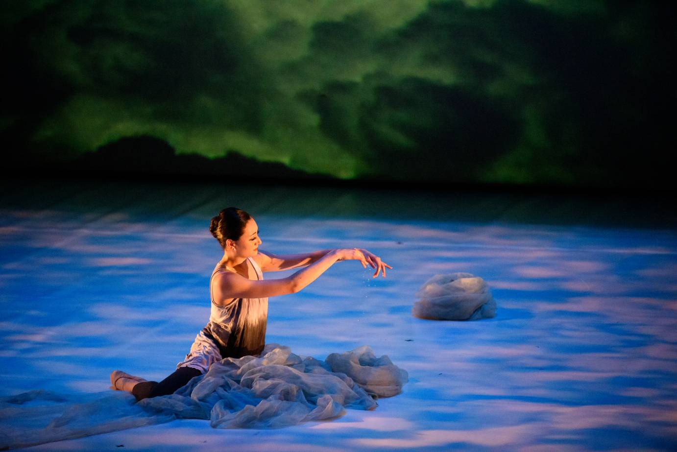 One dancer sits on the floor in a pile of tulle, gesturing