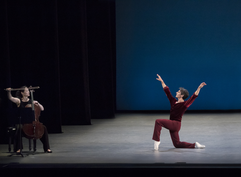 Joaquin de Luz poses on one knee and gestures to cellist Ann Kim seated to the left of him.