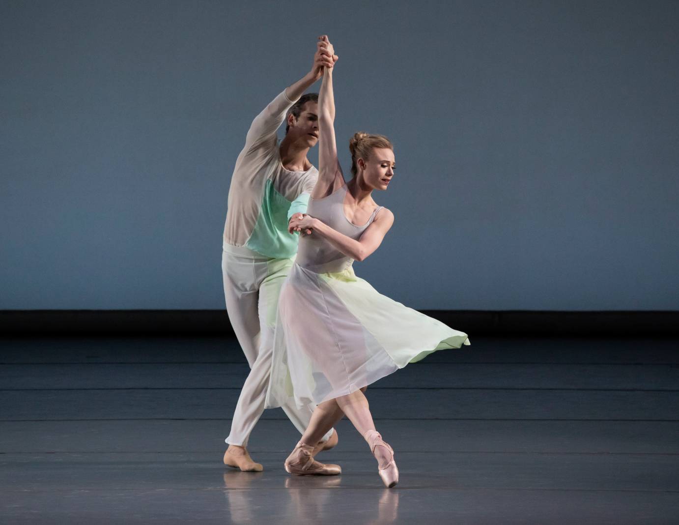 A man holds a woman's arms as she extends her leg