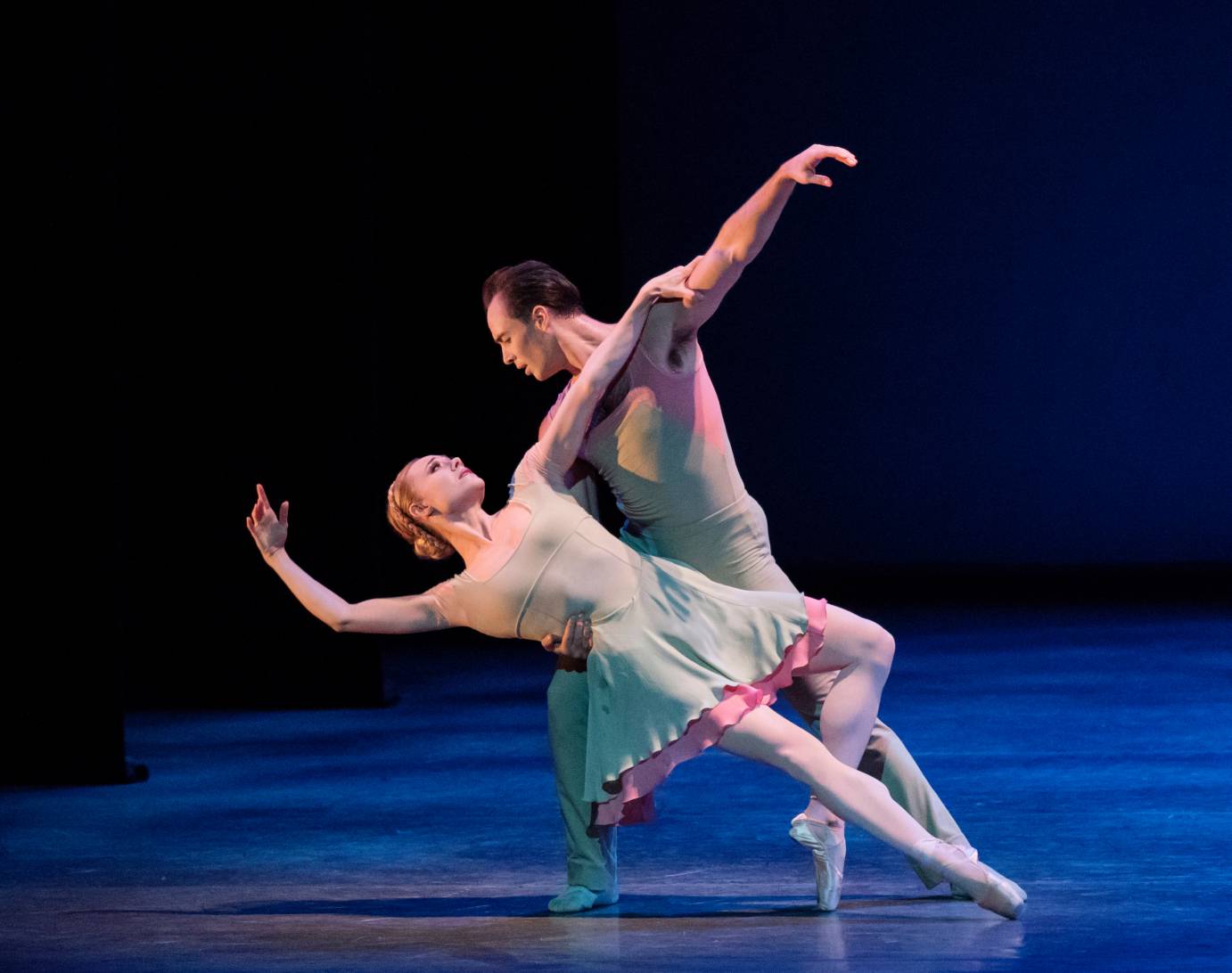 A man dips a woman, both in mint-green costumes