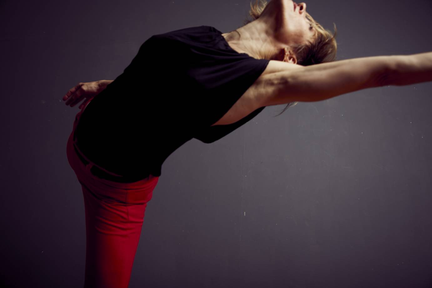 A woman arches her back with one arm extended