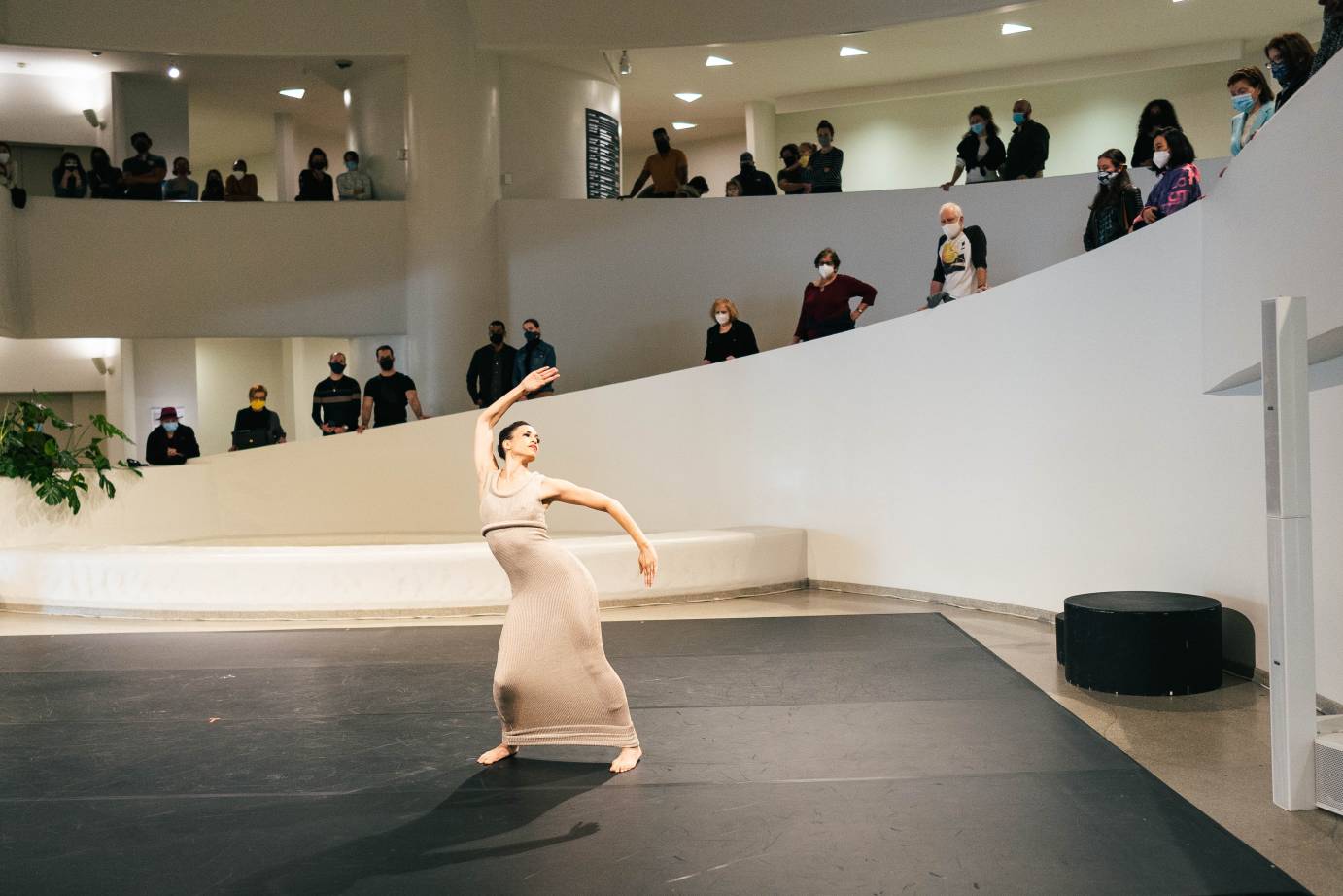 Natasha Diamond-Walker makes an S with her arms as people watch from above