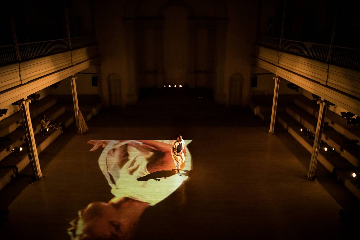 A dancer stands on top of a projection of a face