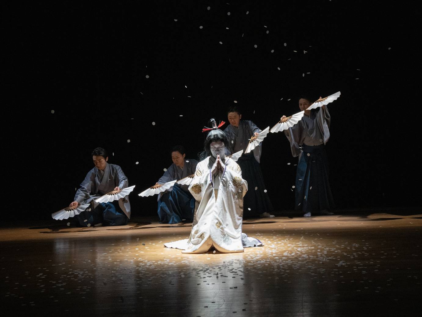 Kyohime, in light-colored sari, full makeup and long black wig, stands centered in front of the four male blue-robed dancers holding a fan in each hand. The fans created a long diagonal from upstage left to downstage right