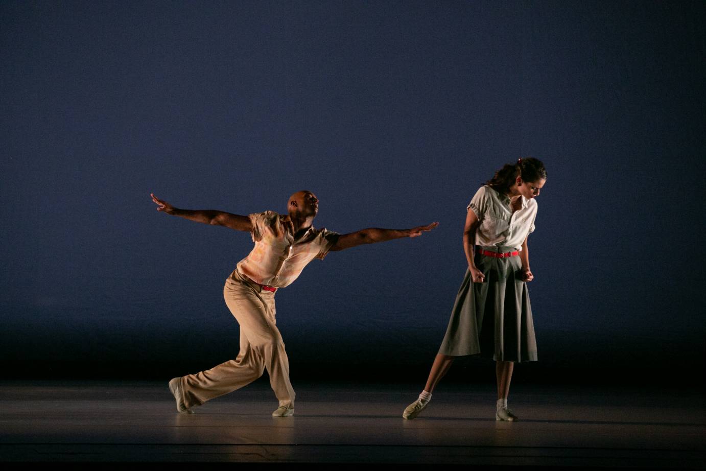 a Black man reaches his arms out almost touching his female partner who stands apart from him and turns her head away from him