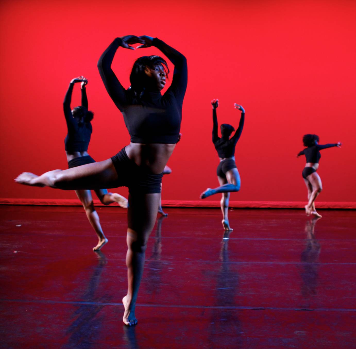 Quartet of female dancers in attitude against a red cyclorama