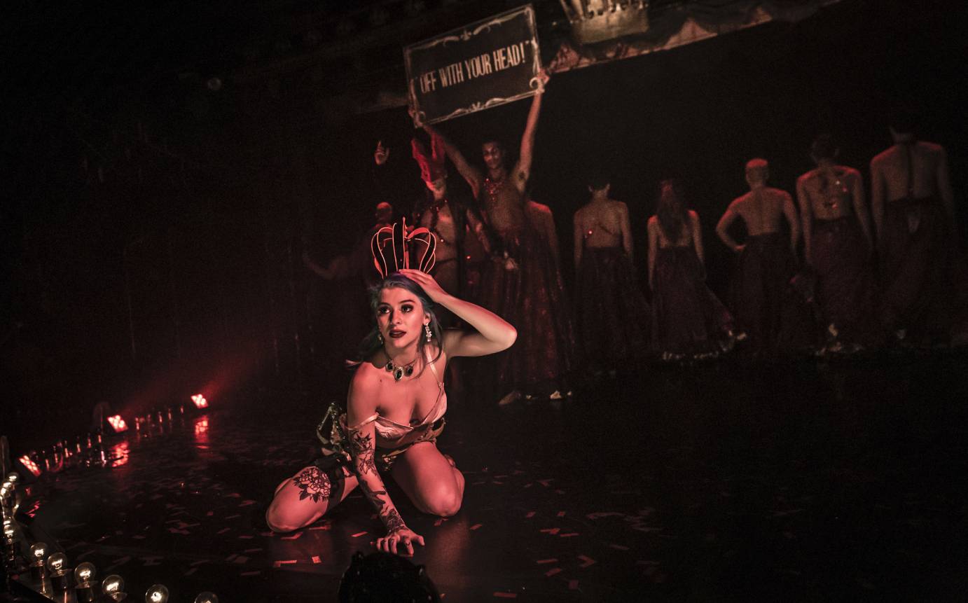 A woman in a crown kneels in a circle of votive candles