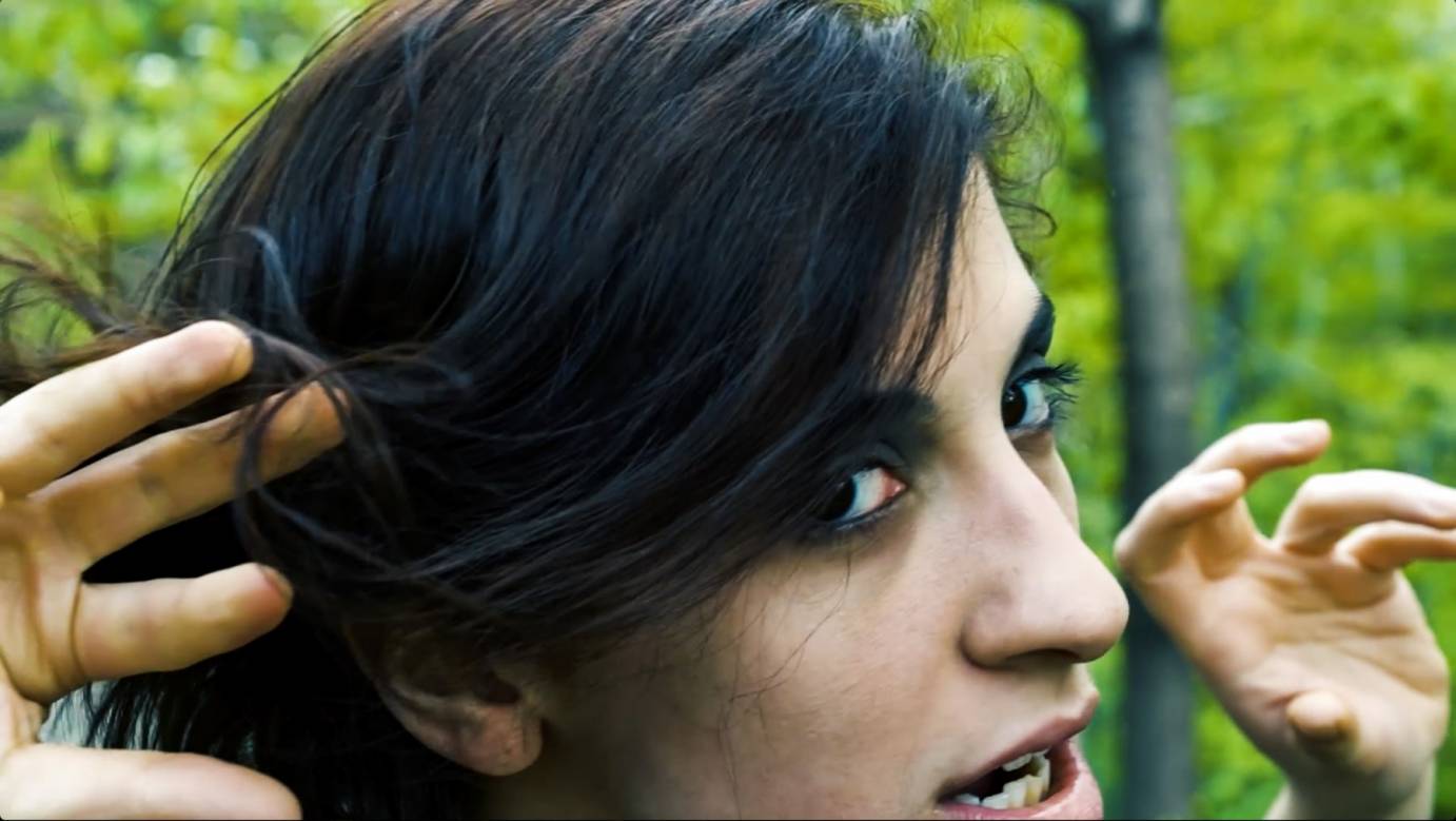 A pale woman with dark eyeliner baring her teeth at the camera.