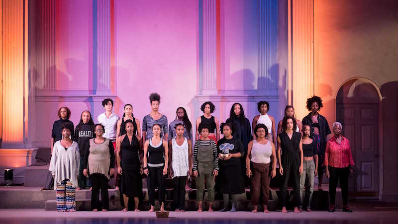 The female cast of the skeleton architecture 2016 performance. They stand in lines on the carpeted stairs of Danspace Project.