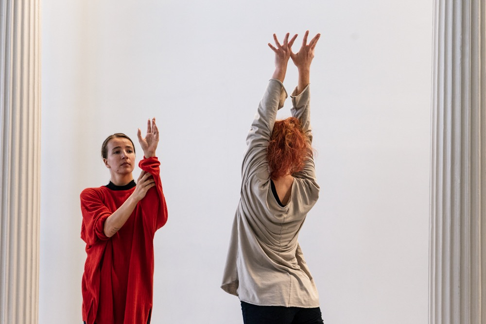 Two women face each other and lift their arms