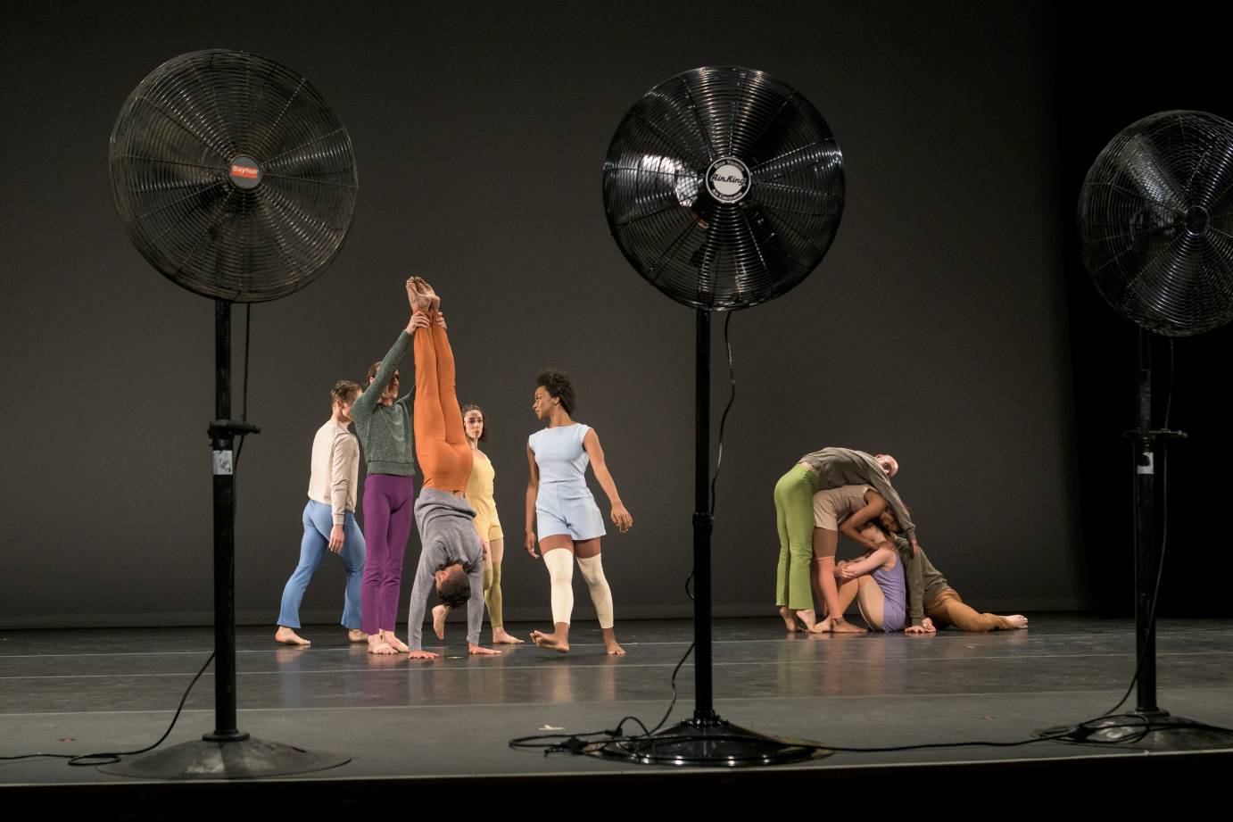 One group of dancers slump over each other while another plays like children