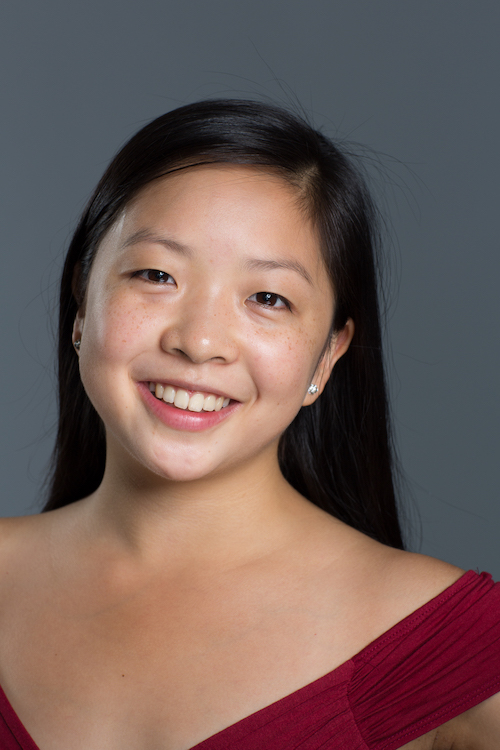 A headshot of dancer Kara Chan who has long black hair and wears a magenta off the shoulder top