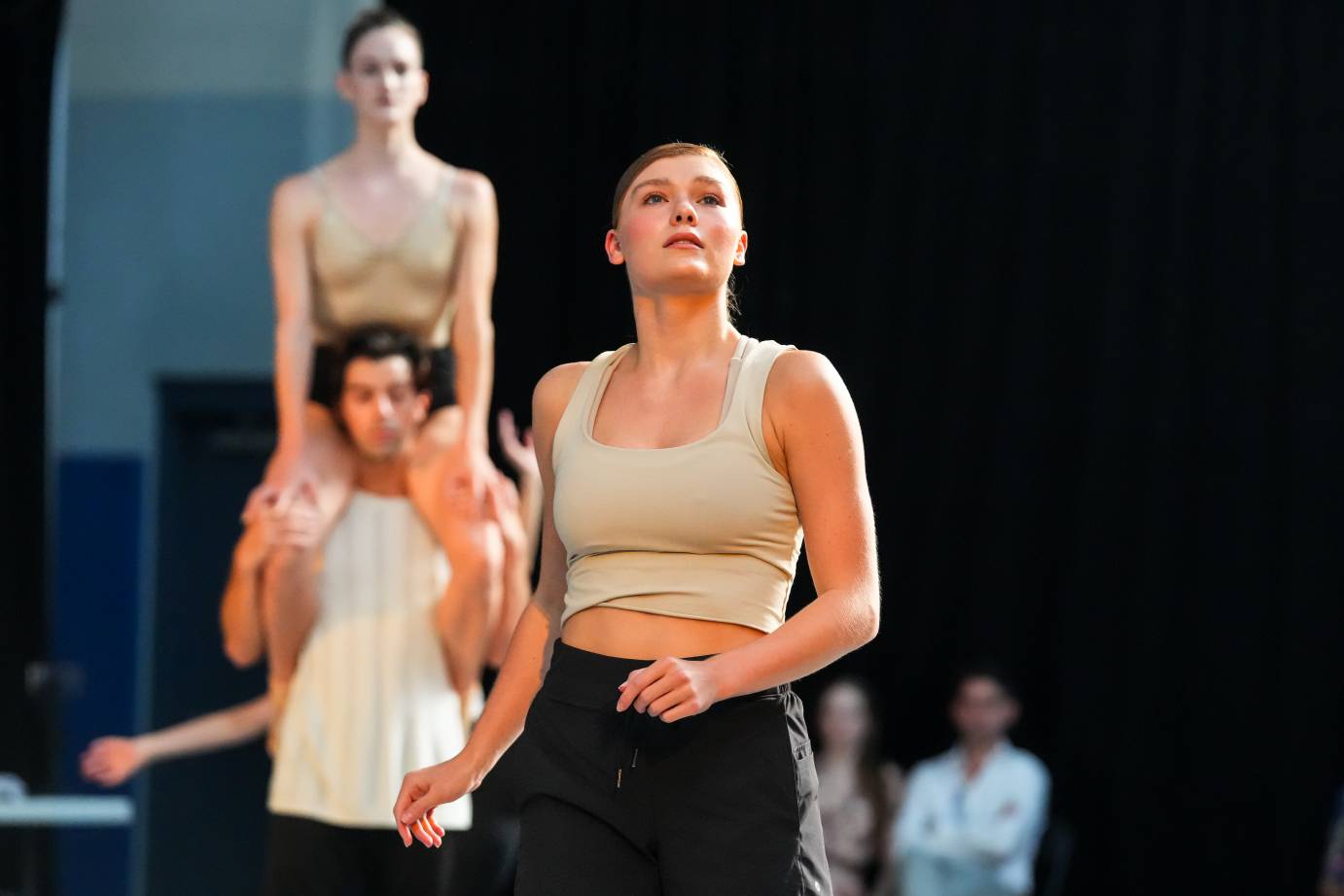 a fair skinned dancer stares to the sky as behind her a man carries a female dancers of his photo 