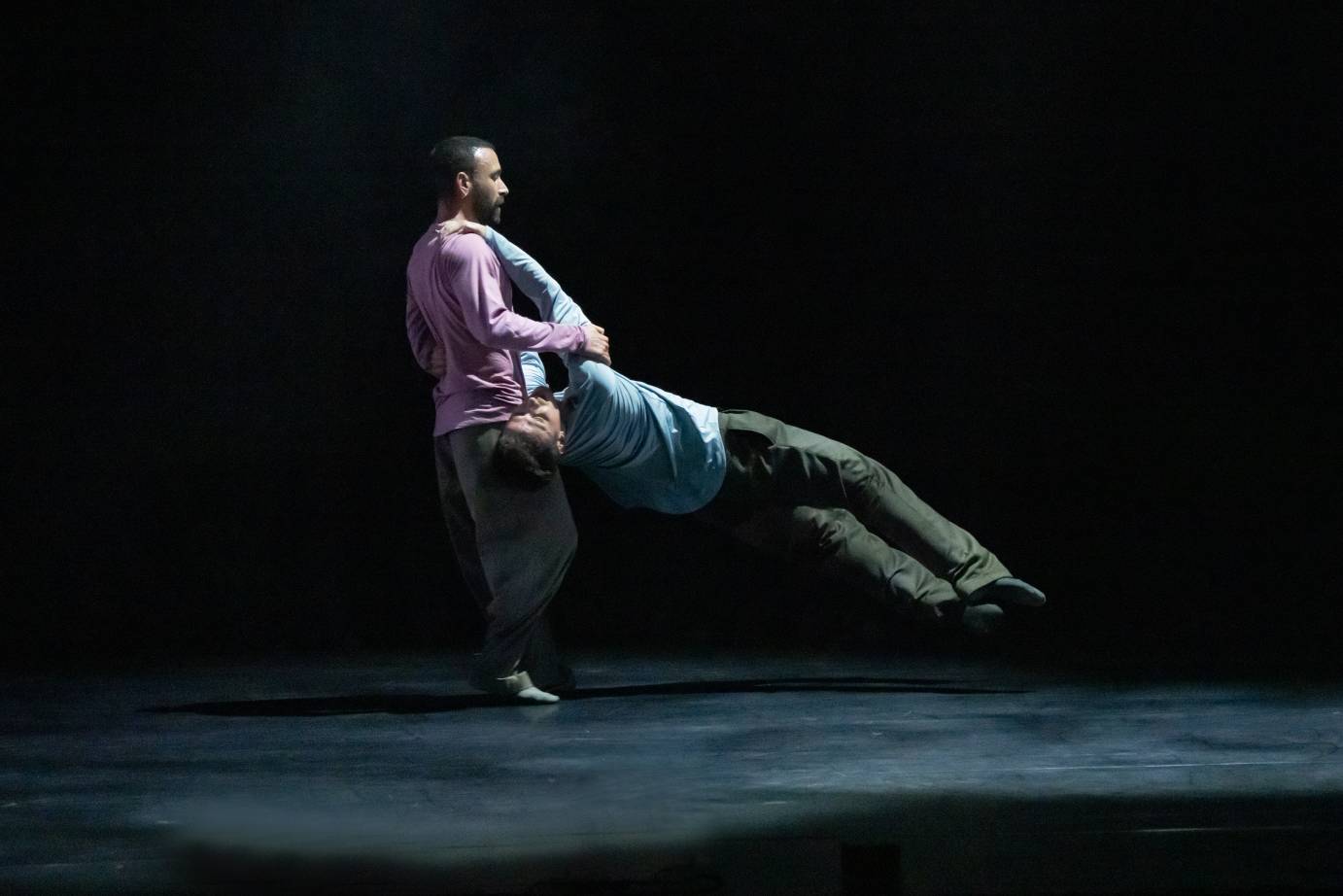 One dancer swings another dancer around in an airplane type lift