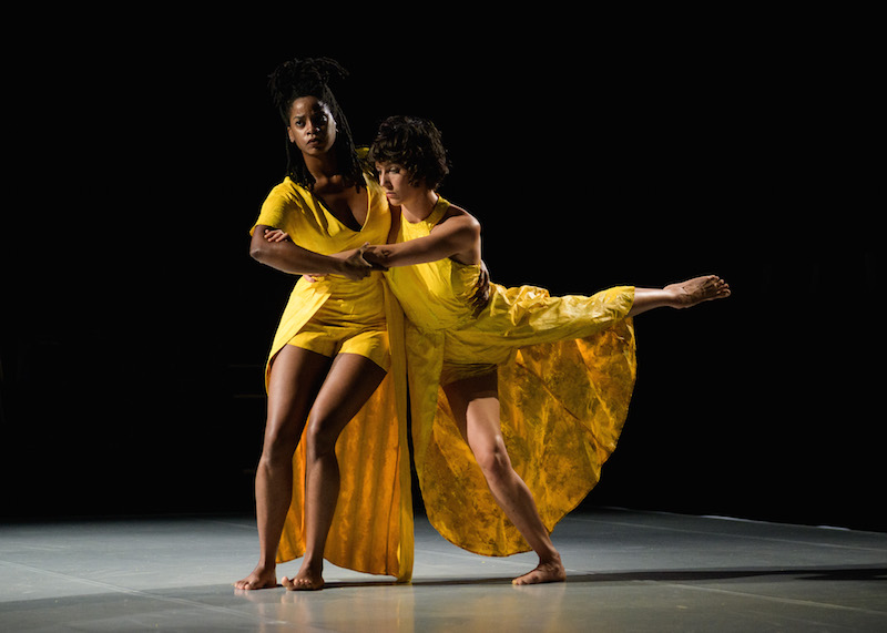 A dancer holds another performer whose leg is balanced in the air in an arabesque position