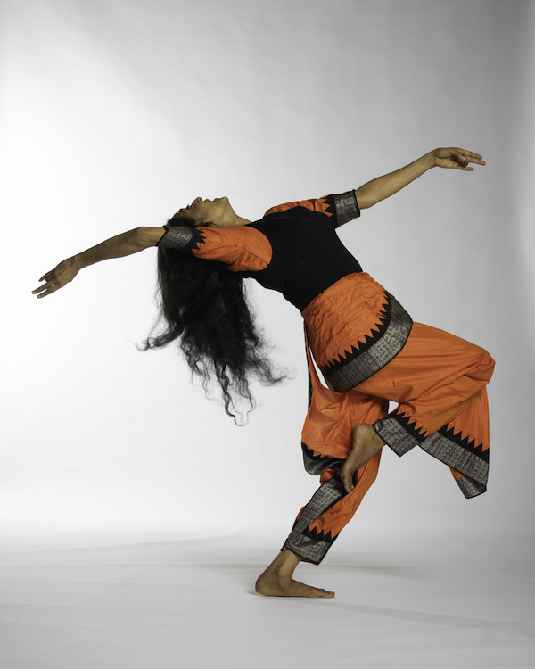 Indian dancer wearing Orange Black and gold traditional costume with long hair in back bend