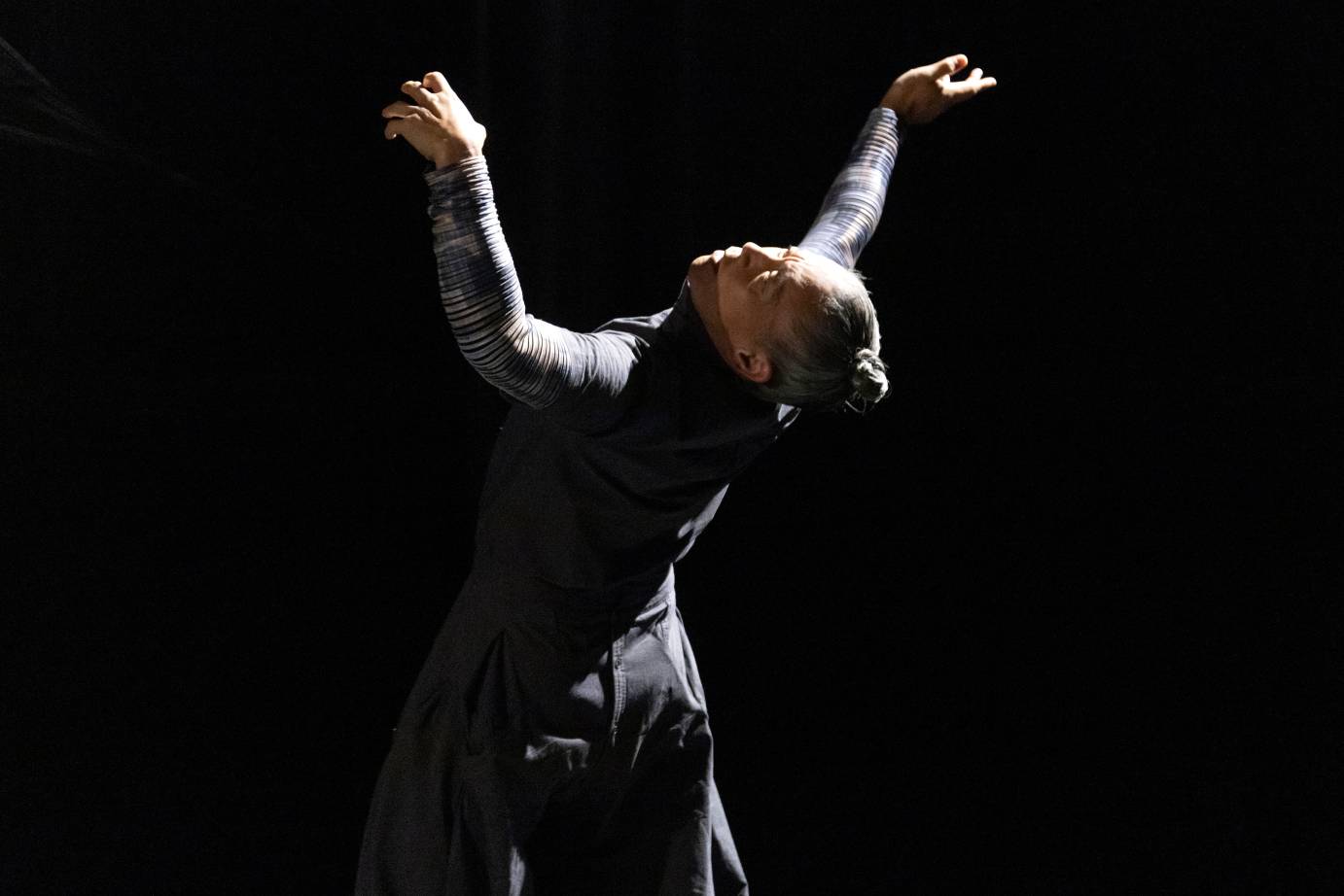 A man arches backward, arms flung upward, head tilted back.