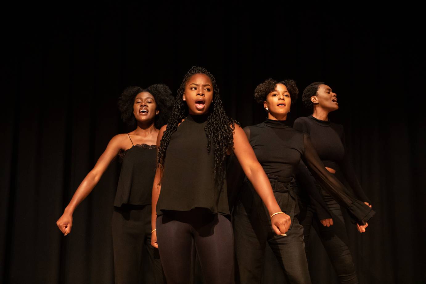 Four Black women costumed in black face the audience with mouths open as if singing or speaking