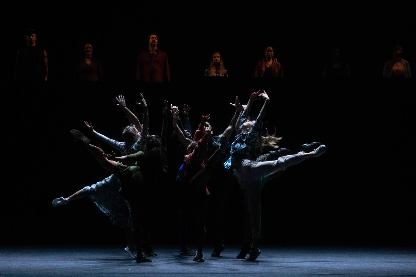 Six dancers jumping in arabesque toward one another forming a circle