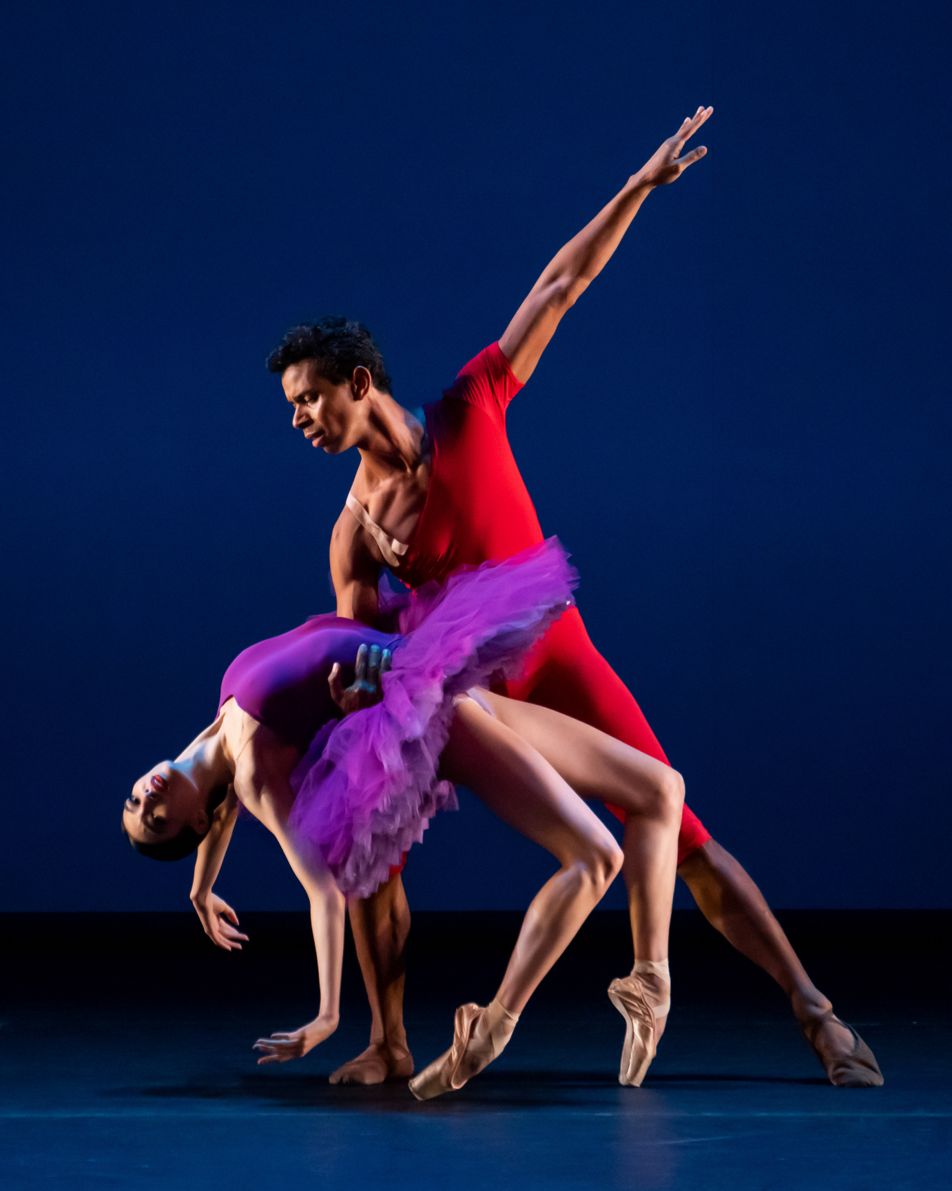 Jose Sebastian dips Chloe Misseldine with one hand. His other arm extends to the ceiling. Misseldine's legs are bent, and she is balanced on the box of her pointe shoes.