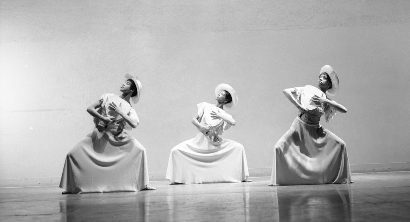 Three women in wide-brimmed hat plié in second position while tilting their body sideways