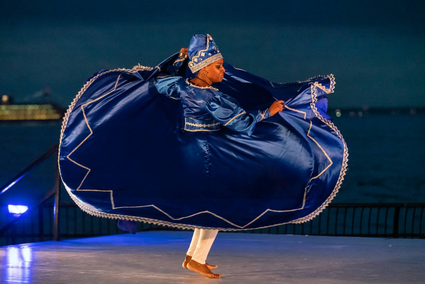 Dressed in midnight-blue circle dress with metallic accents, Beatrice Caputo sweeps the skirt up as she jumps slightly.